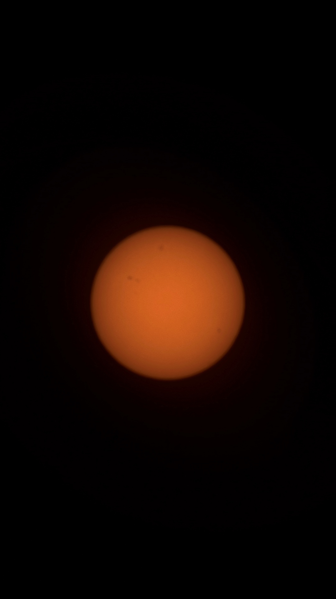 A close-up image of the sun showing a detailed and textured orange surface surrounded by darkness, highlighting sunspots and solar features.